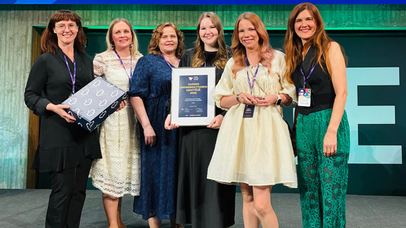 Kuusi henkilöä ryhmäkuvassa lavalla Finnish Learning Awards -tapahtumassa palkintotodistuksen kanssa.