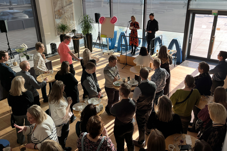 Varmalaisia isossa aulatilassa kuuntelemassa kahta puhujaa