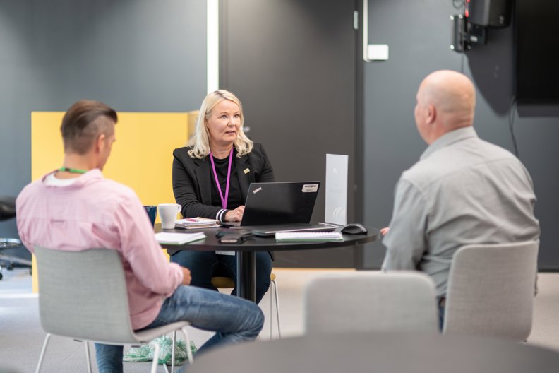 Kuvassa kolme henkilöä keskustelee pöydän ääressä. Varman asiakkuuspäällikkö Kirsti Wall on kasvot kohti kameraa, ja kaksi miestä istuu selkä kameraa kohti.