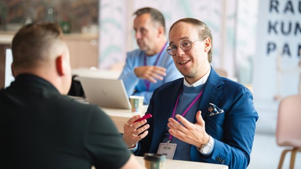 Kaksi miestä keskustelee pöydän ääressä kasvotusten. Varman asiakkuuspäällikkö Niki Koivisto on kasvot kohti kameraa.