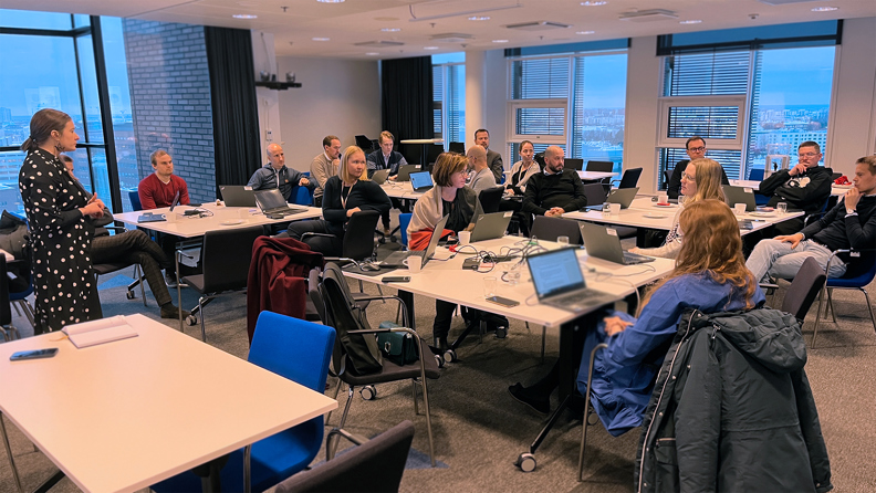 Varmalaisia isossa kokoushuoneessa työpöytien ääressä keskustelemassa. 