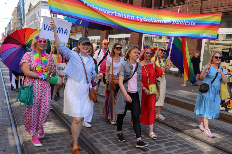 Varmalaisia marssimassa Helsinki Pride -kulkueessa Aleksanterinkadulla Yhdenvertaisen työelämän puolesta -kyltin kanssa vuonna 2024.